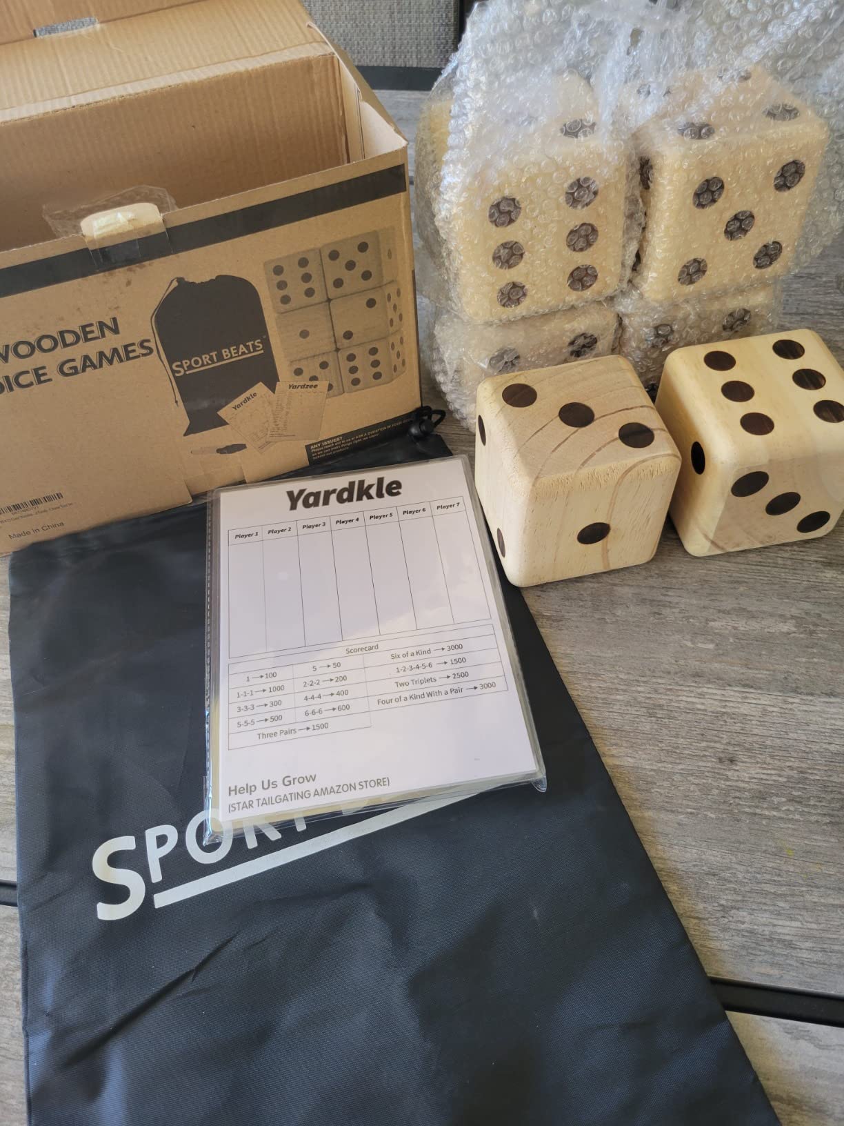 Unboxed set of light wooden yard dice with a black drawstring bag and a Yardkle score sheet